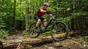 Alt text for image 2: A professional mountain biker riding a lightweight hardtail electric mountain bike across a damp cedar bridge on a misty, technical North Shore trail in British Columbia, surrounded by lush ferns and ancient evergreens.