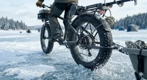 Close-up of heavy-duty studded tires on a fat tire ebike, providing critical traction on a frozen Canadian lake surface.
