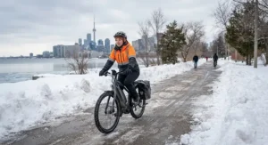 Riding an ebike for winter commuting through a cleared snow-lined bike path in Toronto.