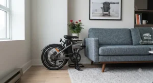 A portable 20 inch folding e-bike neatly folded and tucked away beside a couch in a compact Canadian apartment.