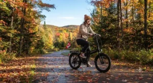 A cyclist enjoying a autumn ride on a folding e-bike under $1000 CAD surrounded by seasonal Canadian foliage.