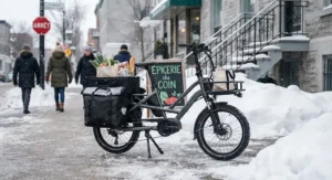 A heavy-duty cargo ebike equipped with panniers parked outside a Montreal local shop in winter.